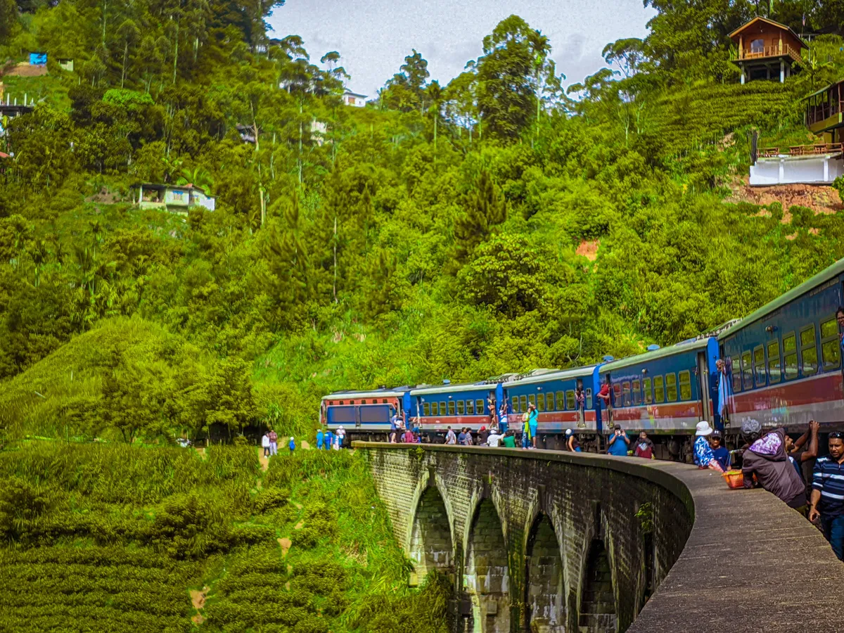 The blue Sri Lankan train crossing the Nine Arch Bridge through green tea-country hills near Ella, Sri Lanka